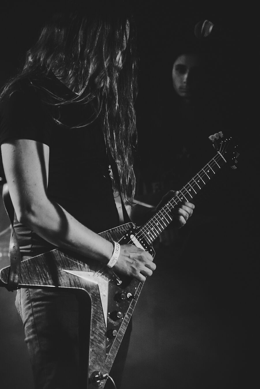 Guitarist playing a Flying V, hair falling across the fretboard