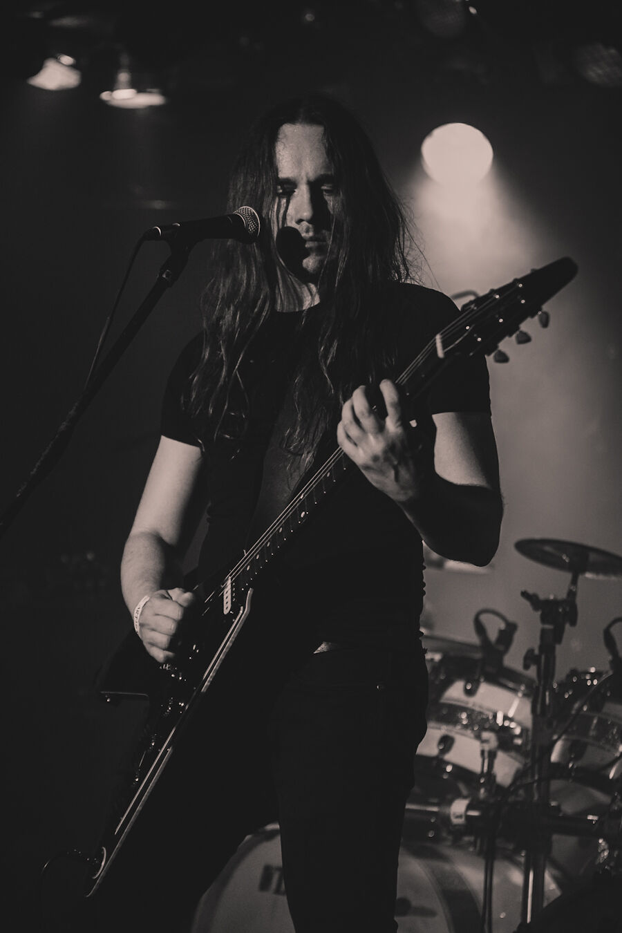 Vocalist and guitarist lit by a single white spotlight