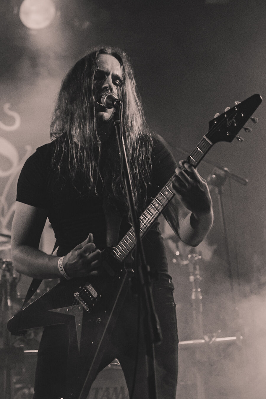 Vocalist screaming into the microphone with a Flying V guitar